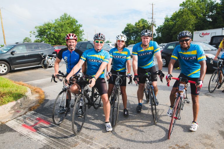 Cyclists on a scenic road during a sponsored charity bike ride.